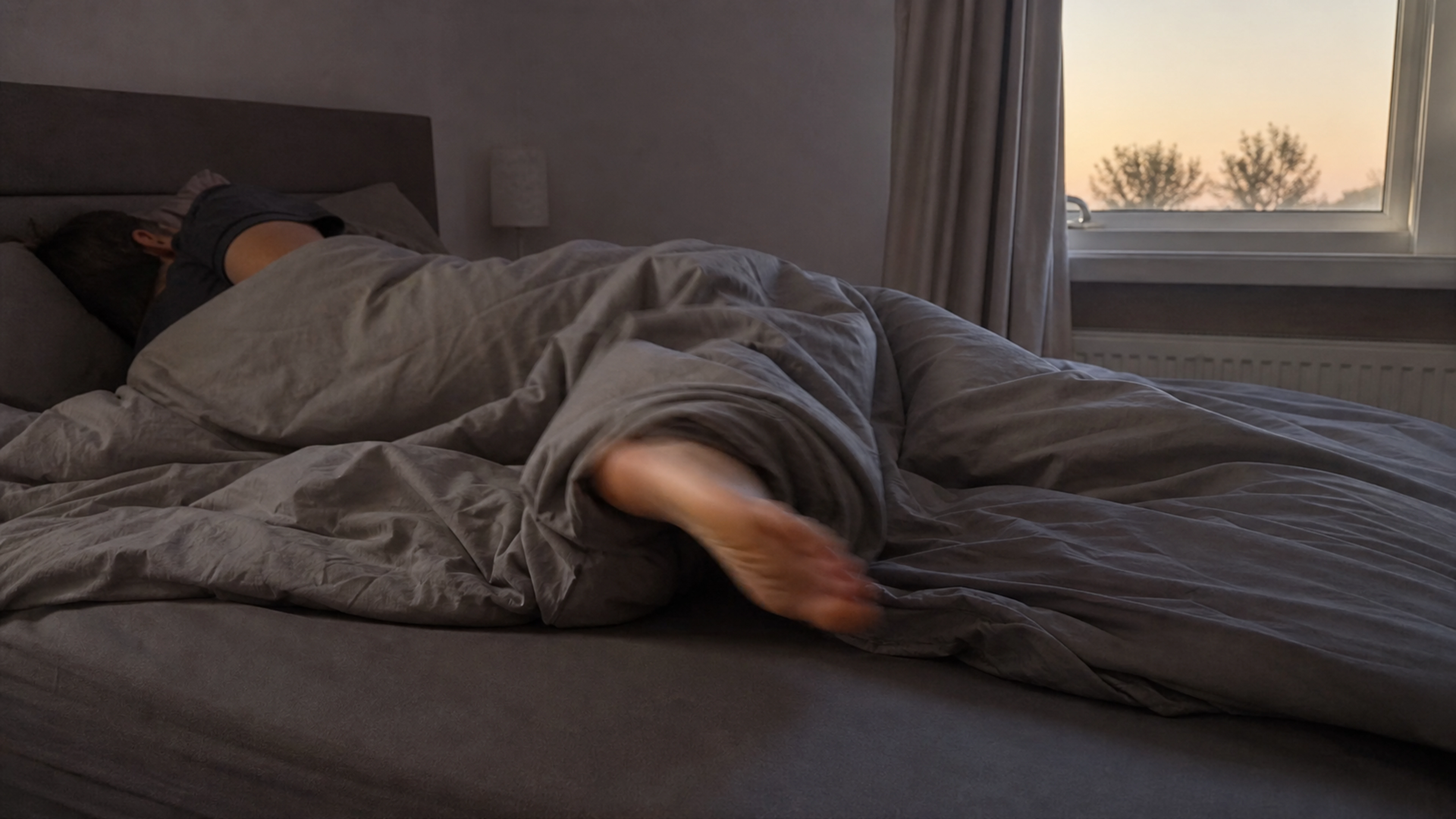 Adulte s'endormant avec un léger sursaut du pied sous la couette