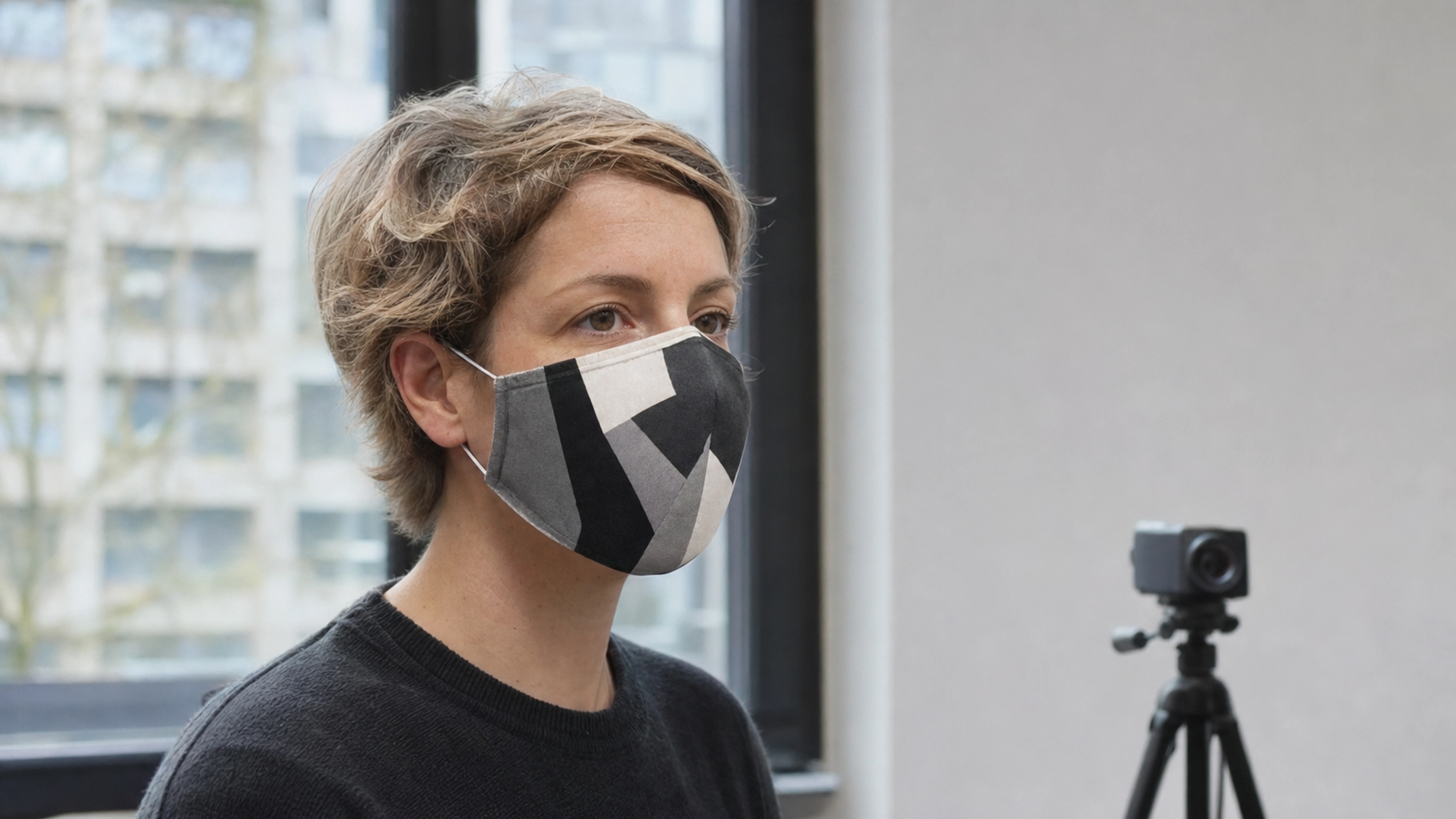 Personne testant un masque textile asymétrique face à une caméra dans un atelier
